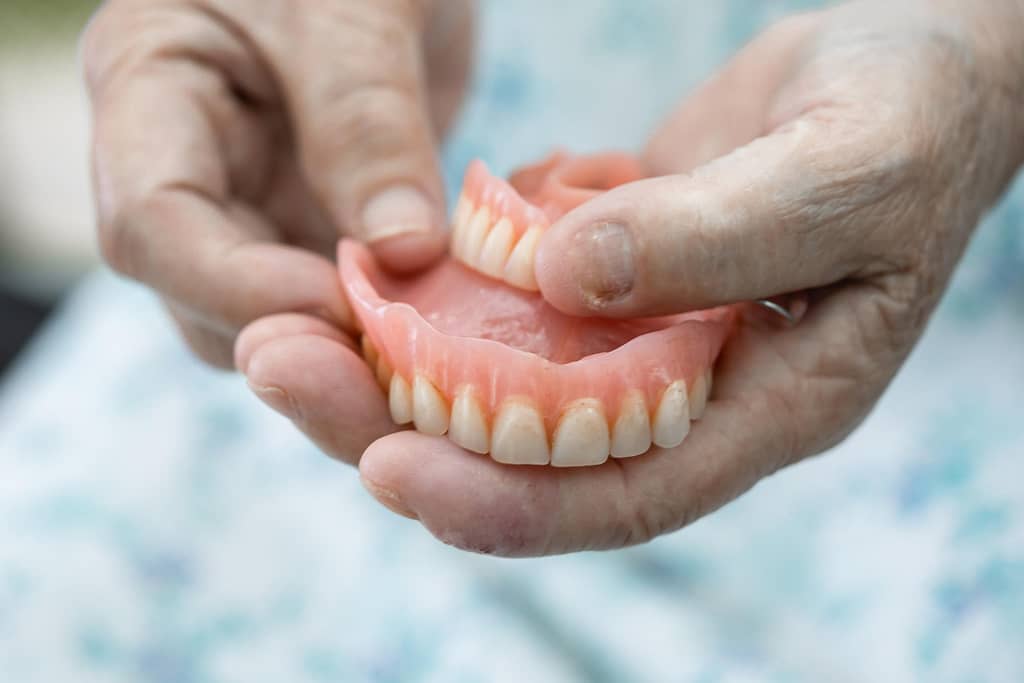 A person holds their dentures in their hands