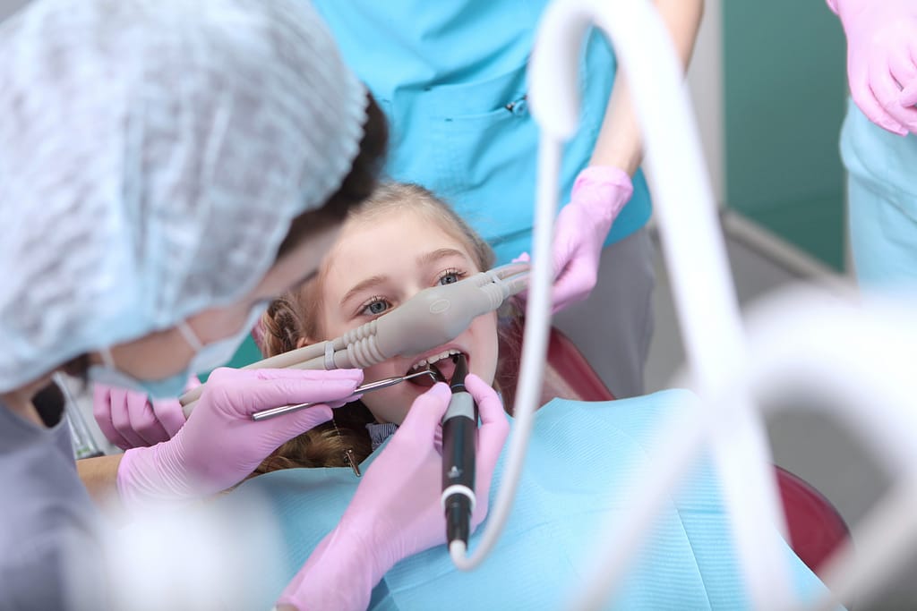 A young girl has nitrous mask on during a dental procedure