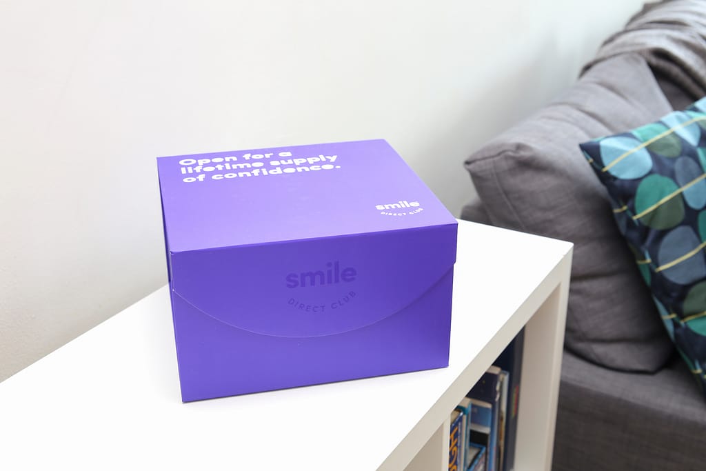 A Smile Direct Club clear aligner box sits on a bookshelf