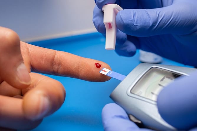 A doctor uses a glucose meter to draw blood and test blood glucose